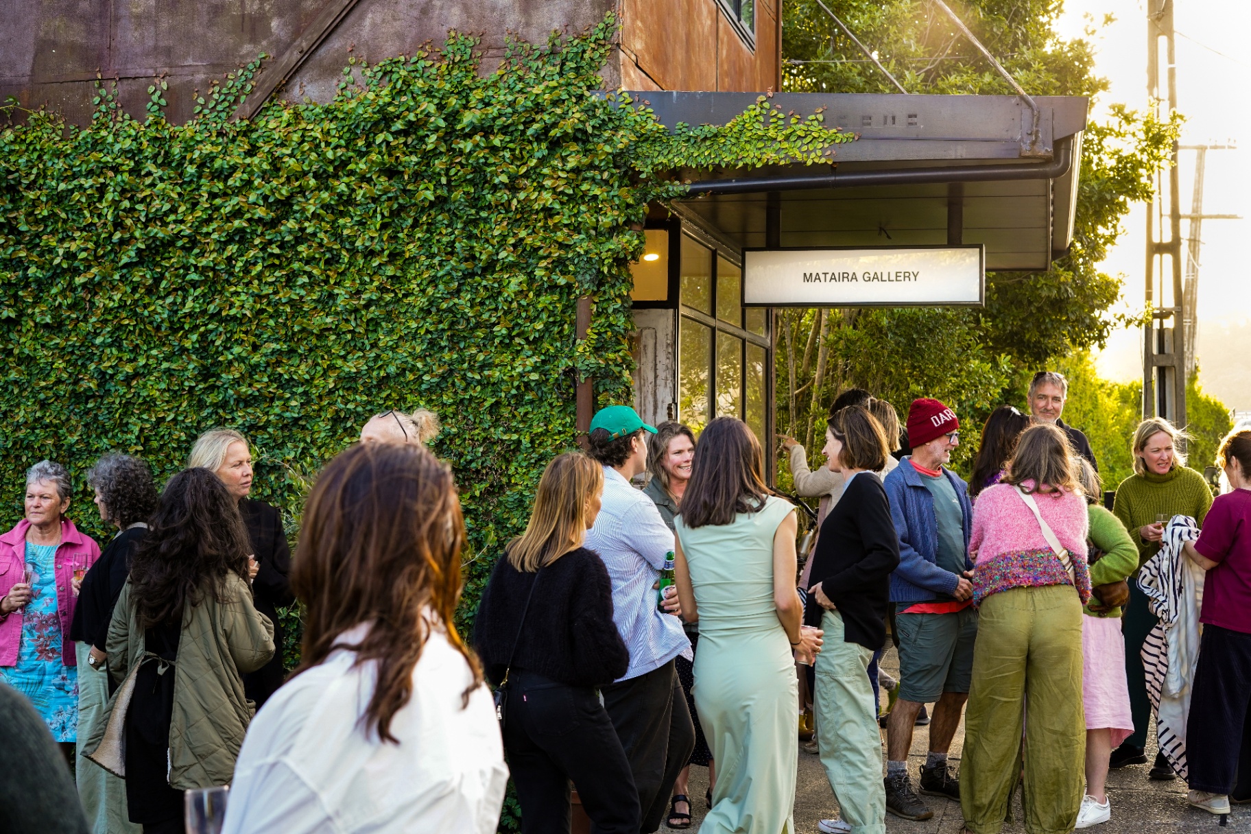 A gathering outside Mataira Gallery, among greenery